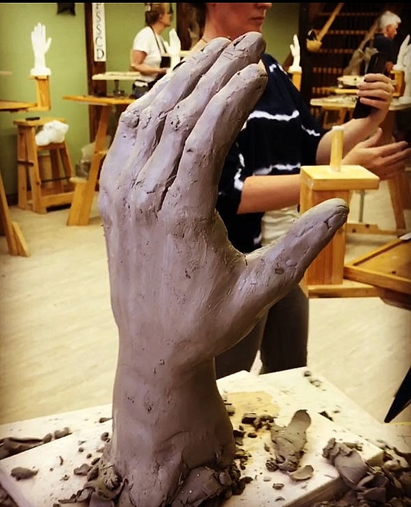 Clay sculpture of a raised hand in progress.