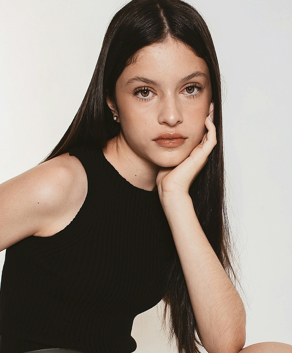 Person with long hair resting chin on hand.