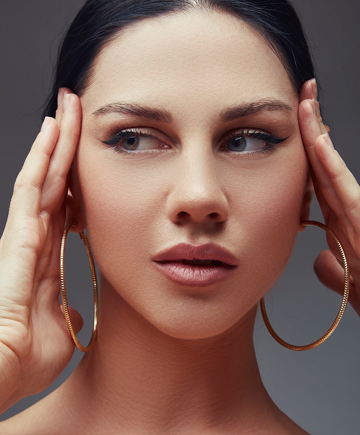 Woman with hoop earrings and elegant makeup.