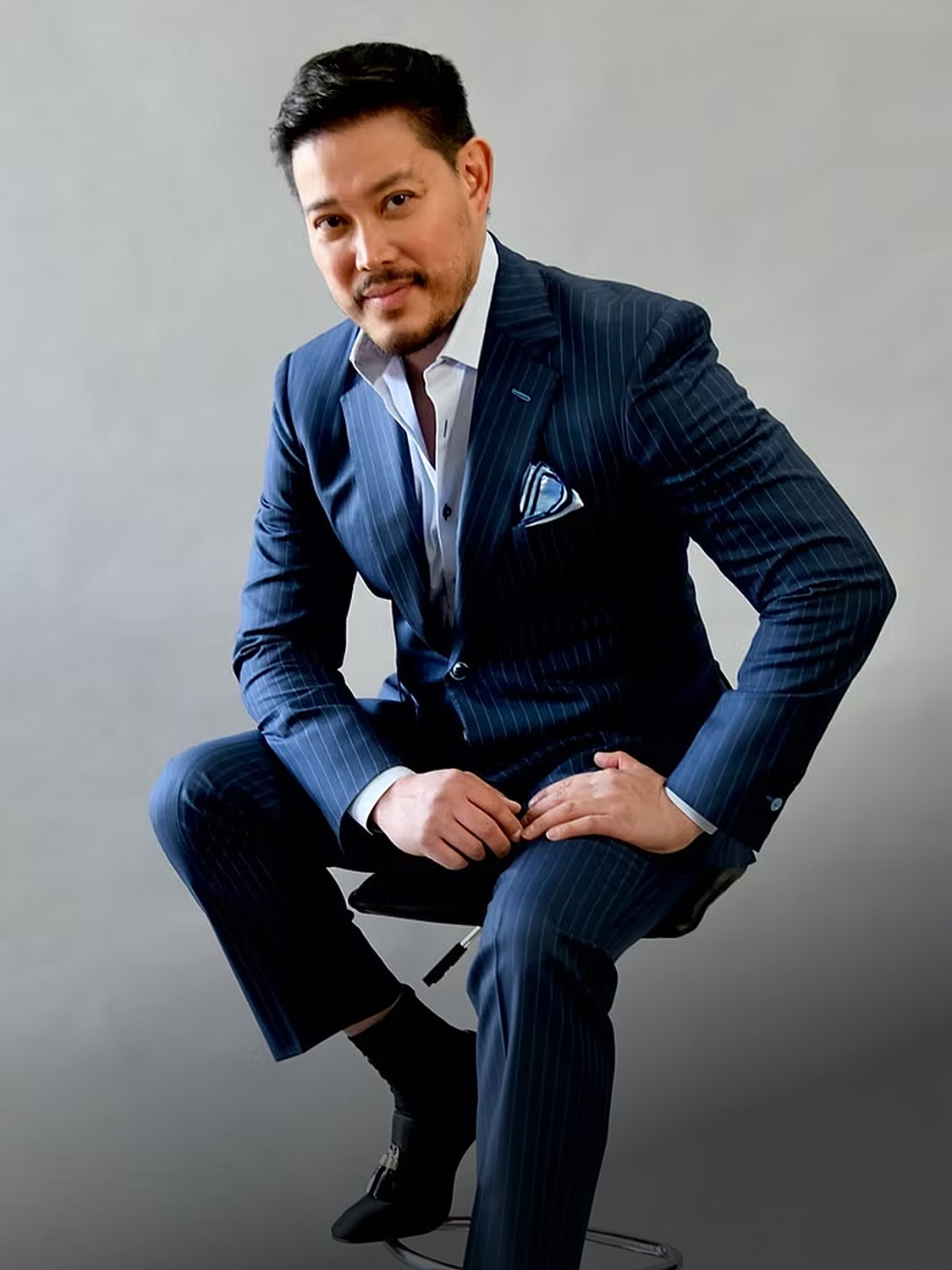 Man in a tailored suit sitting confidently.