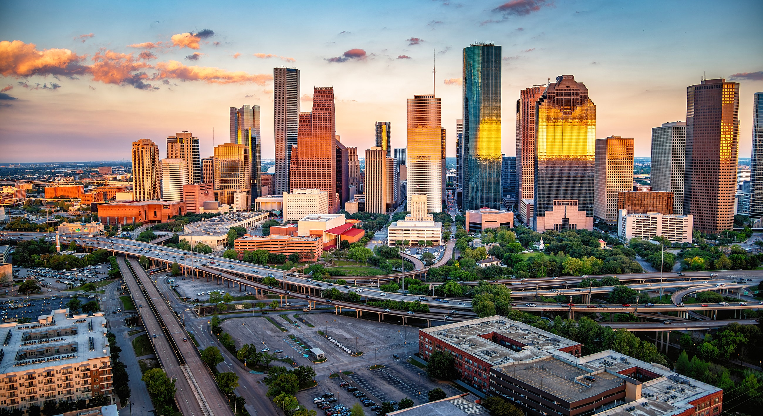 Houston skyline at sunset with highways below.