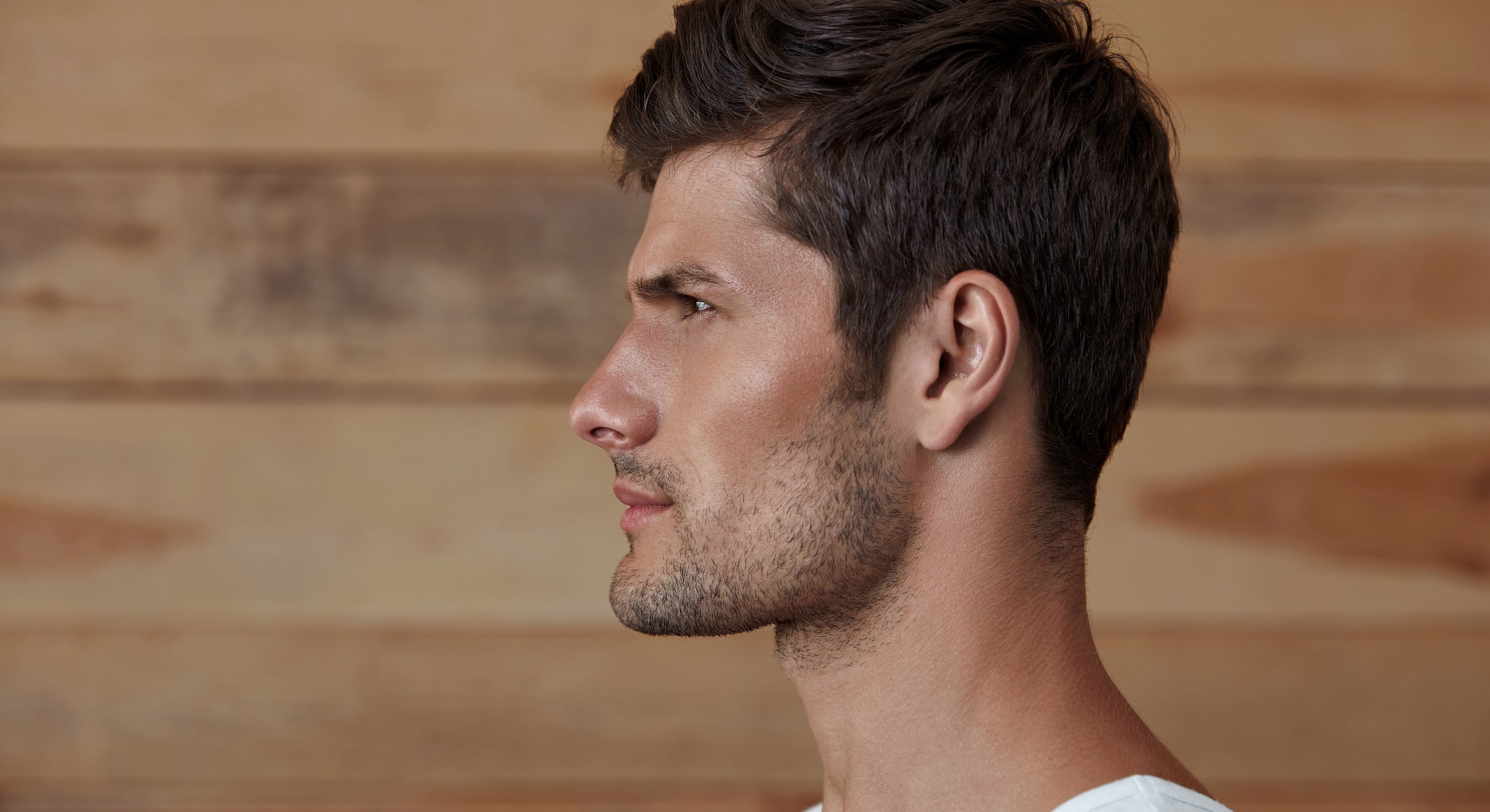 Profile portrait of a man against wooden background.