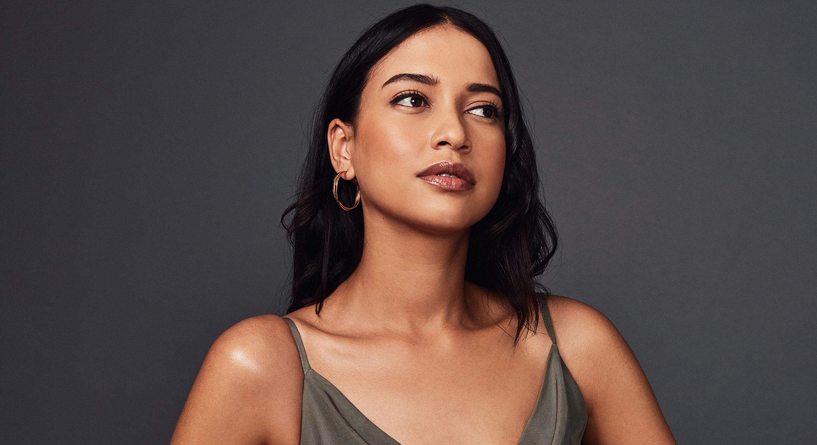 Confident woman in casual attire, neutral background.